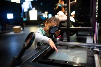 Young visitor engrossed in exhibit's digital display.